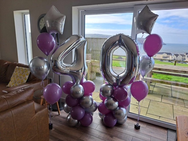 Silver and lilac foil balloon display beside a window