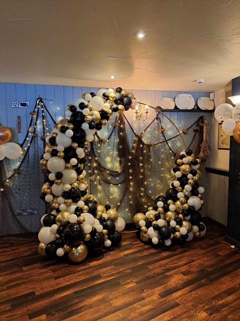 Black and gold balloon arch backdrop for a celebration