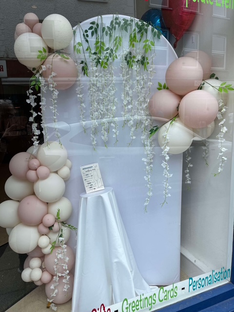 White display backdrop decorated with blush and green balloons