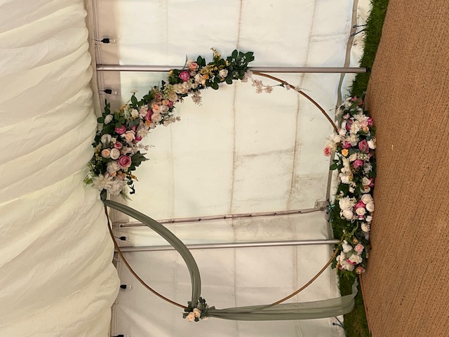 Round ceremony hoop with floral garland and sage draping
